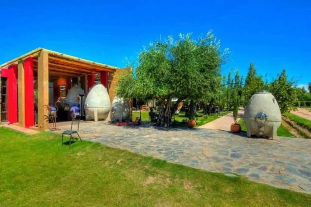 Jardim de uma vinícola com ânforas de barro e um alpendre ao fundo