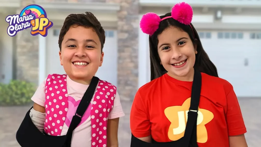 Dupla infantil sorrindo em frente a uma casa, com o logotipo do canal
