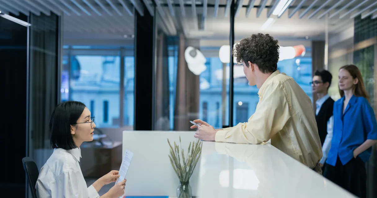 Atendente e cliente conversando no balcão de recepção de um escritório moderno